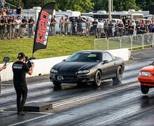 Black car doing a burnout on a drag strip