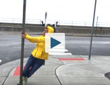 Woman holding on to sign in high winds